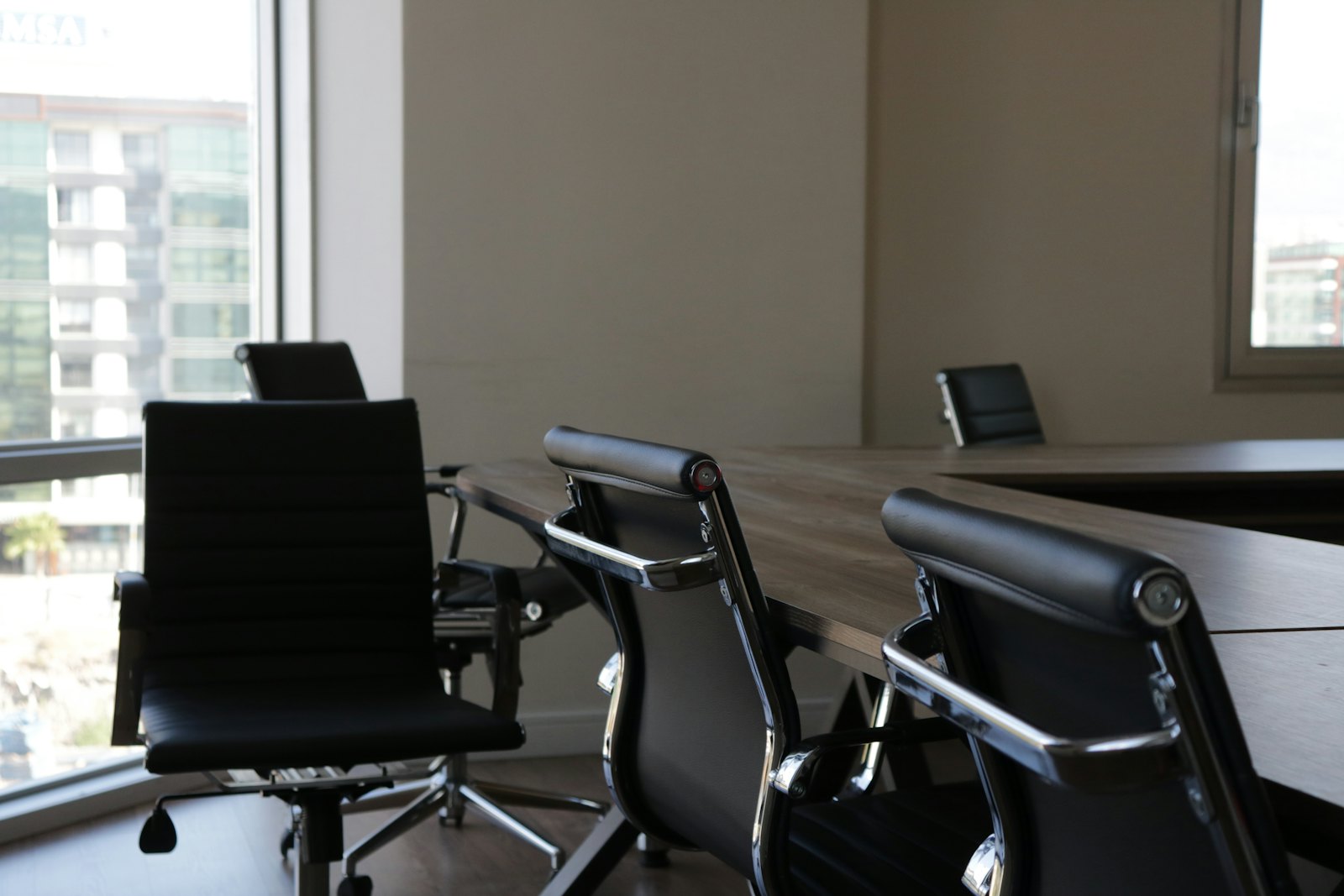 Sala de reuniões com mesa de madeira e cadeiras executivas